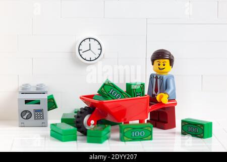 Tambov, Russian Federation - December 23, 2020 Lego businessperson minifigure transporting money in a wheelbarrow. Stock Photo