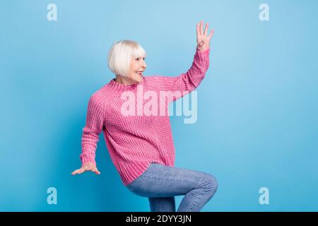 Photo portrait of positive old woman dancing making claws with hands isolated on pastel blue colored background Stock Photo