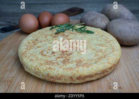 Tasty spanish omelette called tortilla de patatas with fresh potatoes and eggs on wooden board.Closeup view classic spanish cuisine concept. Stock Photo