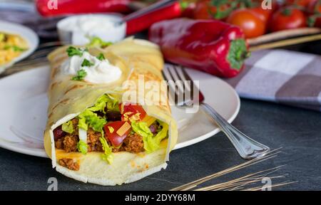 healthy pancake with spicy minced meat, vegetables and sour cream topping. Mexican style Stock Photo