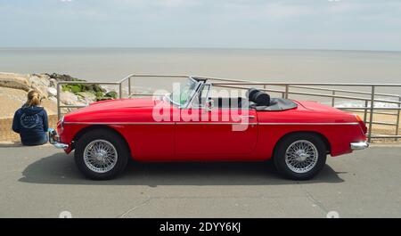 Classic  Red  MG Roadster  Car  parked on seafront promenade with sea in background. Stock Photo