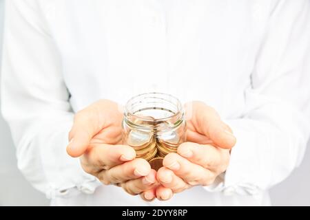 Hand with coins in a glass jar. Money growth, savings and investment concept. Stock Photo