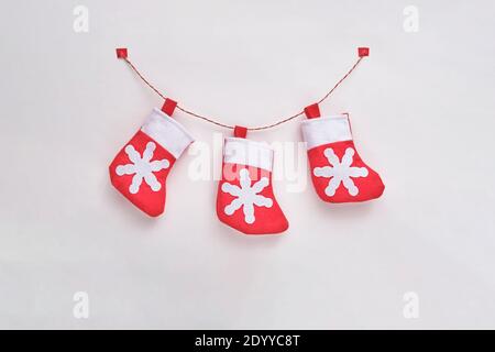 Three red and white toy textile Christmas socks on the tape on the white background. Top view. Stock Photo