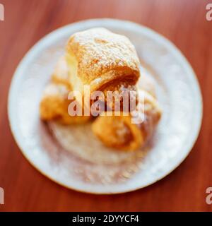 Fresh crispy croissants on a silver vintage plate on the wooden table. Stock Photo