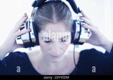 woman with a set of retro corded headphones.Vintage Analog sound.woman listening to music on her headphones , white background Stock Photo