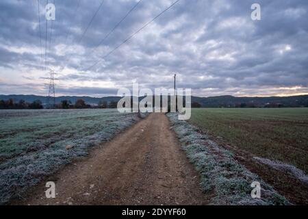 Frozen green rural landscape on a gravel road way under a snowy cloudscape sky Stock Photo