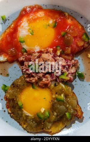 Traditional Mexican breakfast huevos divorciados eggs with tomato and verde salsa served with homemade refried beans Stock Photo
