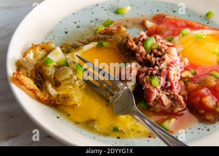 Traditional Mexican breakfast huevos divorciados eggs with tomato and verde salsa served with homemade refried beans Stock Photo