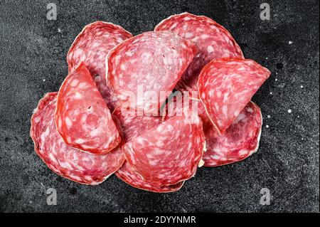 Slices of spanish salami salchichon. Black background. Top view Stock Photo