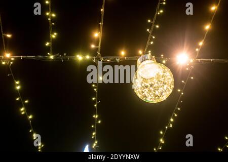 Bright light bulbs garlands hang on a rope against the background of the sky Stock Photo