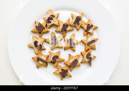Merry Christmas gingerbread star cookies with chocolate and icing on white plate Stock Photo