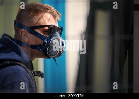 Young man wears an N99 respirator half mask and sunglasses. The man is protecting himself from coronavirus and other airborne particles and diseases. Stock Photo