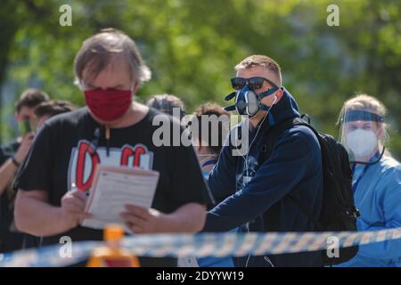 People wearing cloth face masks or respirators waiting in long queue for a test as part of a study on collective immunity against the corona virus. Stock Photo
