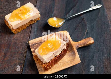 Gingerbread with foie gras and a teaspoon with candied onion on the dark old wooden background Stock Photo