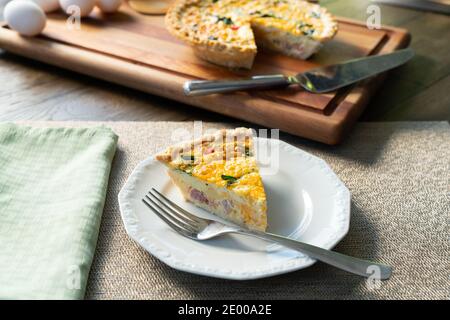 Fresh slice of quiche lorraine on a white plate Stock Photo