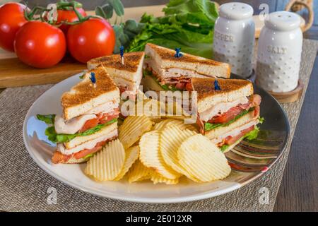 Fresh turkey club sandwich on white toast with potato chips on a plate Stock Photo