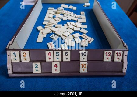 Legendary game okey and game table. Turkish board game Okey (Rummikub). A table with green cloth and chips. Hands of the players. Stock Photo