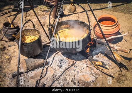 Stew or soup in iron pot or cauldron on a campfire. Homemade food at historical reenactment of Slavic or Vikings lifestyle Cedynia, Poland Stock Photo