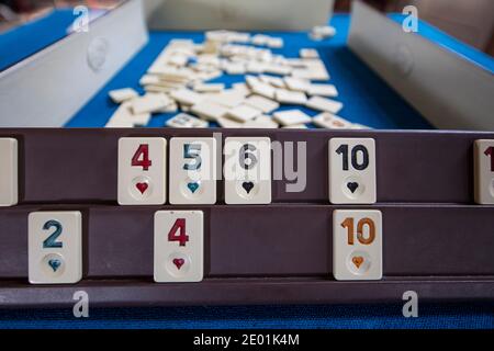 Legendary game okey and game table. Turkish board game Okey (Rummikub). A table with green cloth and chips. Hands of the players. Stock Photo