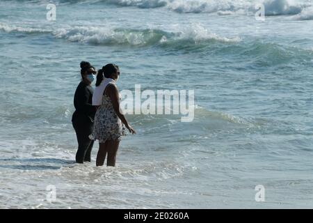 People, women standing in sea water on beach, seaside holiday, Durban, South Africa, leisure activity, Covid 19 pandemic mask, Corona virus, disease Stock Photo