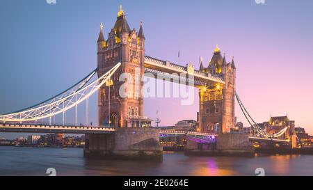 The lights of the iconic Tower Bridge come on as the sun sets over the Thames in London, England Stock Photo