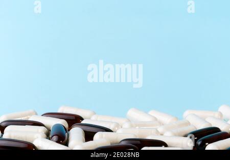 Medicine or supplement capsules on blue surface. Pharmaceutical pills and vitamins. Probiotic, glucosamine chondroitin pile. Stock Photo