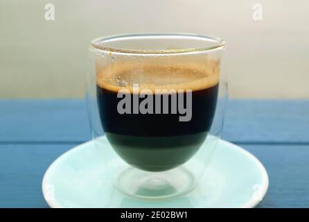 Glass of hot black coffee isolated on blue wooden table Stock Photo