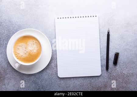 Office desk with cup of coffee, note pad, smartphone and supplies. Top view. Copy space - Image Stock Photo