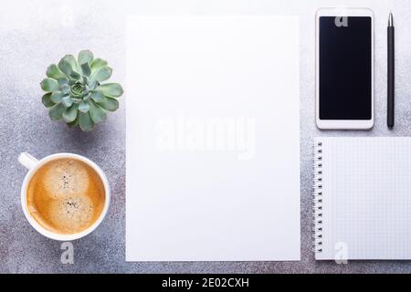 Office workplace with blank paper, cup of coffee, smartphone, green succulent and pen. Top view. Stone background. Copy space Stock Photo
