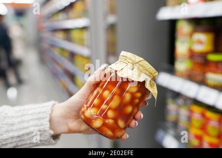 Woman holding canned beans in tomato sauce in the store Stock Photo