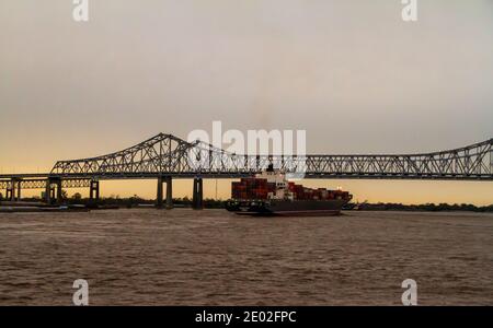 Container ship passing under the cantilever Crescent City Connection bridges on the MIssissippi River at the port of New Orleans, Louisiana, USA. Stock Photo