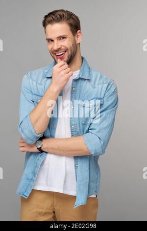 Portrait of young handsome caucasian man in jeans shirt over light background Stock Photo