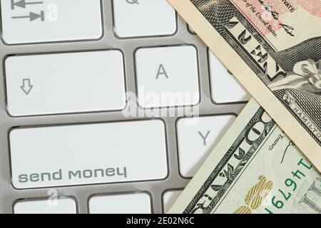 A computer, dollar bills and button send money Stock Photo