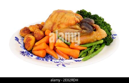 Roasted whole Guinea fowl with roast potatoes and fresh vegetables isolated on a white background Stock Photo