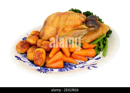 Roasted whole Guinea fowl with roast potatoes and fresh vegetables isolated on a white background Stock Photo