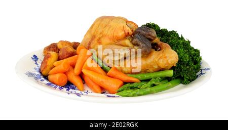 Roasted whole Guinea fowl with roast potatoes and fresh vegetables isolated on a white background Stock Photo