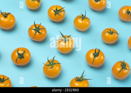 Cherry tomatoes on a colored blue background. Pattern and minimal background of yellow tomatoes Stock Photo