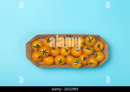 Cherry tomatoes on a colored blue background. Cherry tomatoes in a package from a supermarket. Fresh vegetables for healthy food concept. Stock Photo