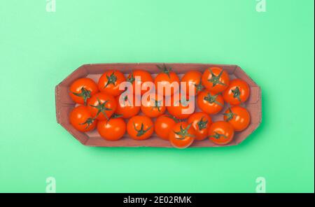 Cherry tomatoes on a colored green background. Cherry tomatoes in a package from a supermarket. Fresh vegetables for healthy food concept. Stock Photo