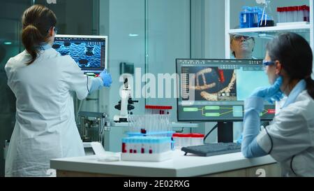 Scientists coworkers working in chemical modern equipped laboratory overtime. Doctors stuff examining vaccine evolution using high tech and technology researching treatment against covid19 virus Stock Photo