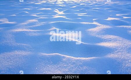 Ground covered by snow, sunlight and shadow on the snow, closeup of snow texture Stock Photo