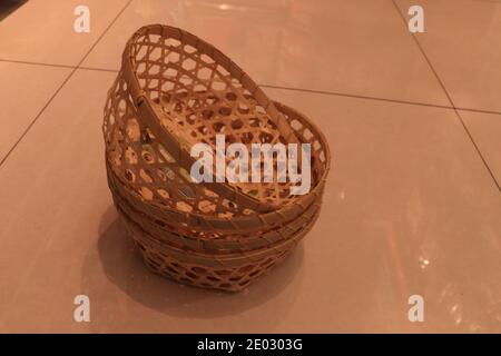 Four handmade bamboo woven draining baskets stacked on the indoor floor. Stock Photo