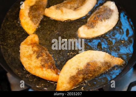 Gyoza dumplings with mushroom filling frying in hot pan. Golden crunchy dumplings cooking in oil. Stock Photo
