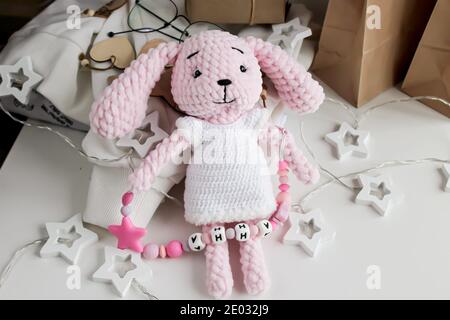 Pink knitted eared hare toy lies on the table. Translate: Anna Stock Photo