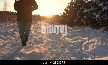 Walk the Snow Trail to Sunset. Man Walks in the Snow in Backlit Sunlight Stock Photo