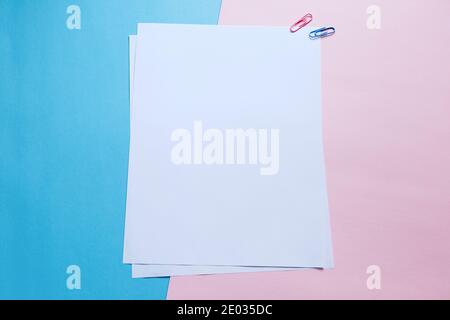 Two white blank papers and clips on pink and blue background Stock Photo