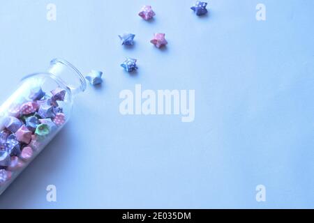 Colorful lucky paper stars with patterns in glass bottle isolated on blue table Stock Photo
