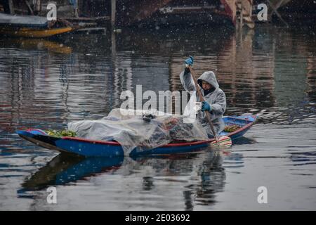 Srinagar, India. 29th Dec, 2020. A boatman rows his vegetable laden boat during fresh snowfall in Srinagar.Fresh snowfall was recorded in parts of Kashmir valley including the summer capital, Srinagar leading to the closure of the Srinagar-Jammu National Highway, officials said. Credit: SOPA Images Limited/Alamy Live News Stock Photo