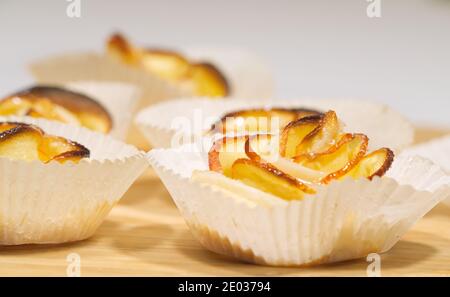 Homemade rose-shaped dessert, buns of dough with apple slices on the kitchen board Stock Photo