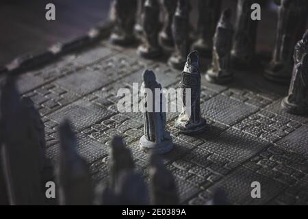 A portrait of a stone chess board. The game of strategy is just begon with two pawns of each army facing eachother in the duel. Stock Photo